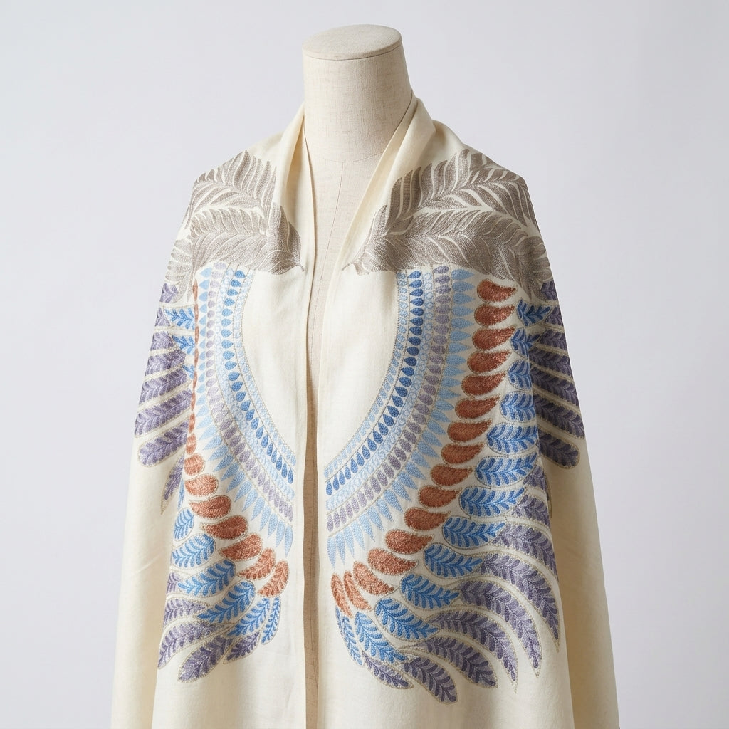 Mannequin wearing a cream-colored scarf with a colorful leaf pattern on a white background