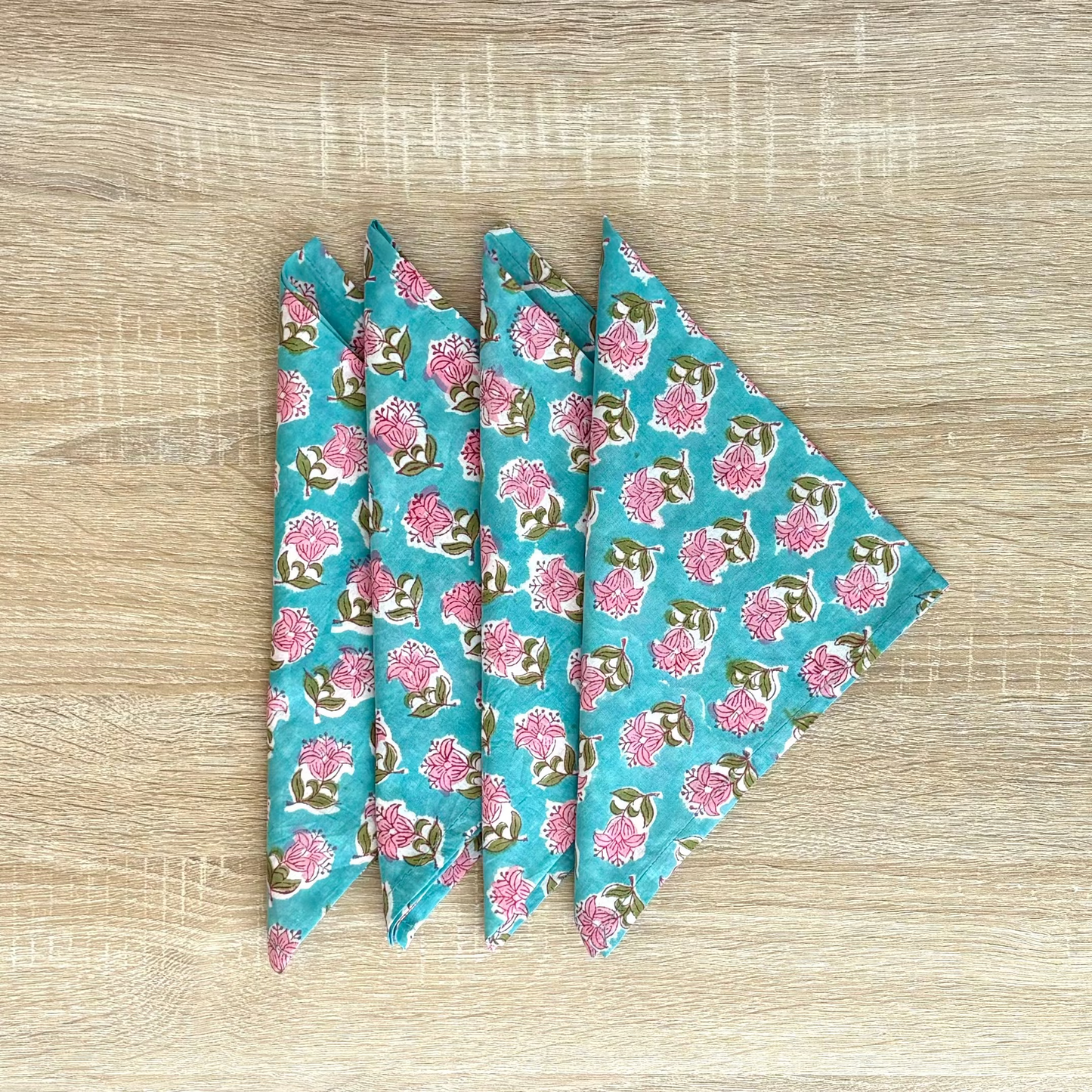 Three blue floral-patterned fabric triangles on a wooden surface