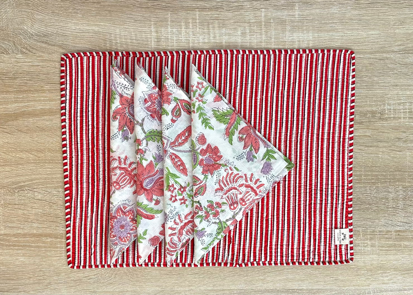 Set of floral-patterned napkins on a red and white striped placemat on a wooden surface