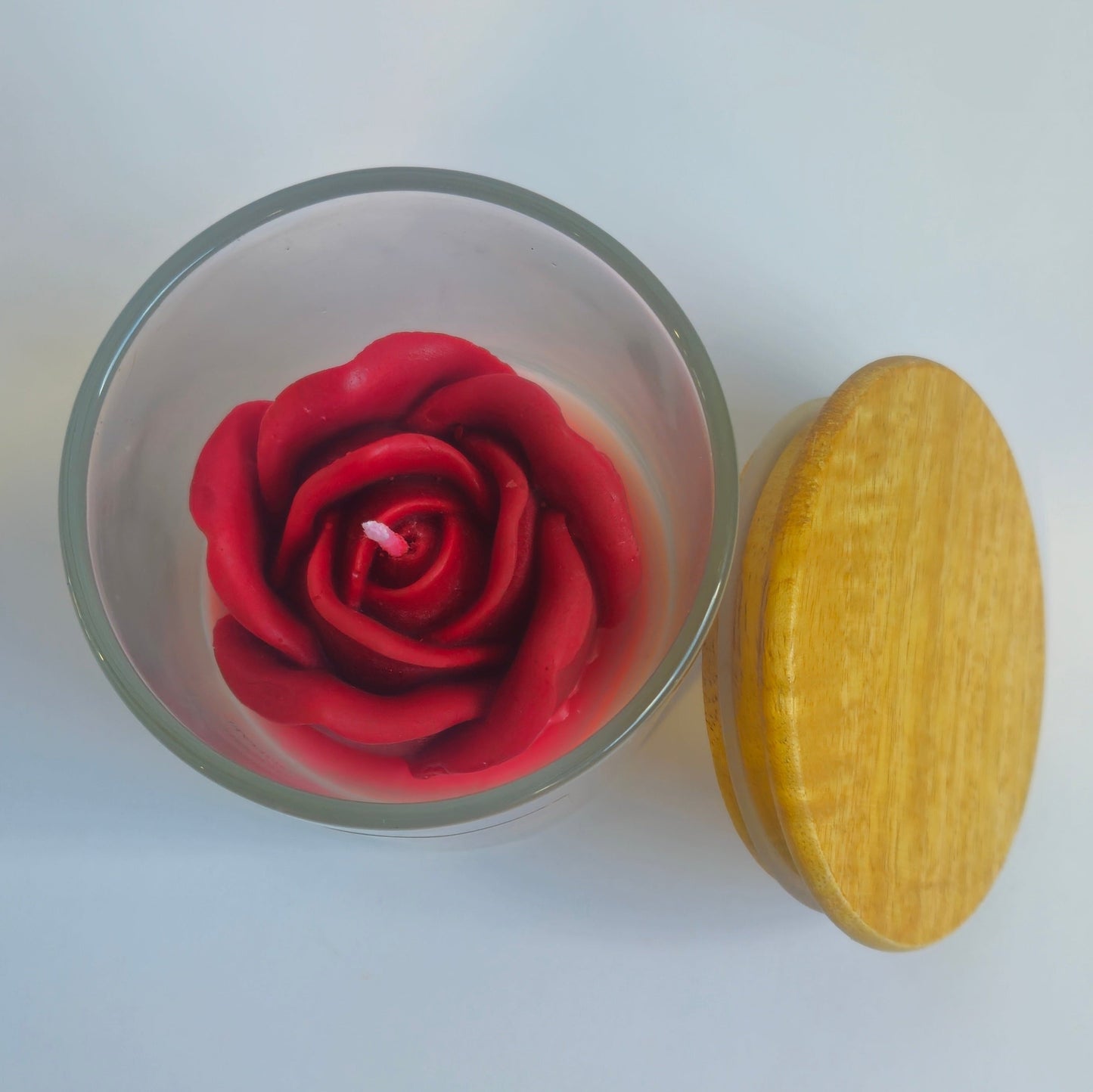 Glass container with a red rose and a yellow object on a white background