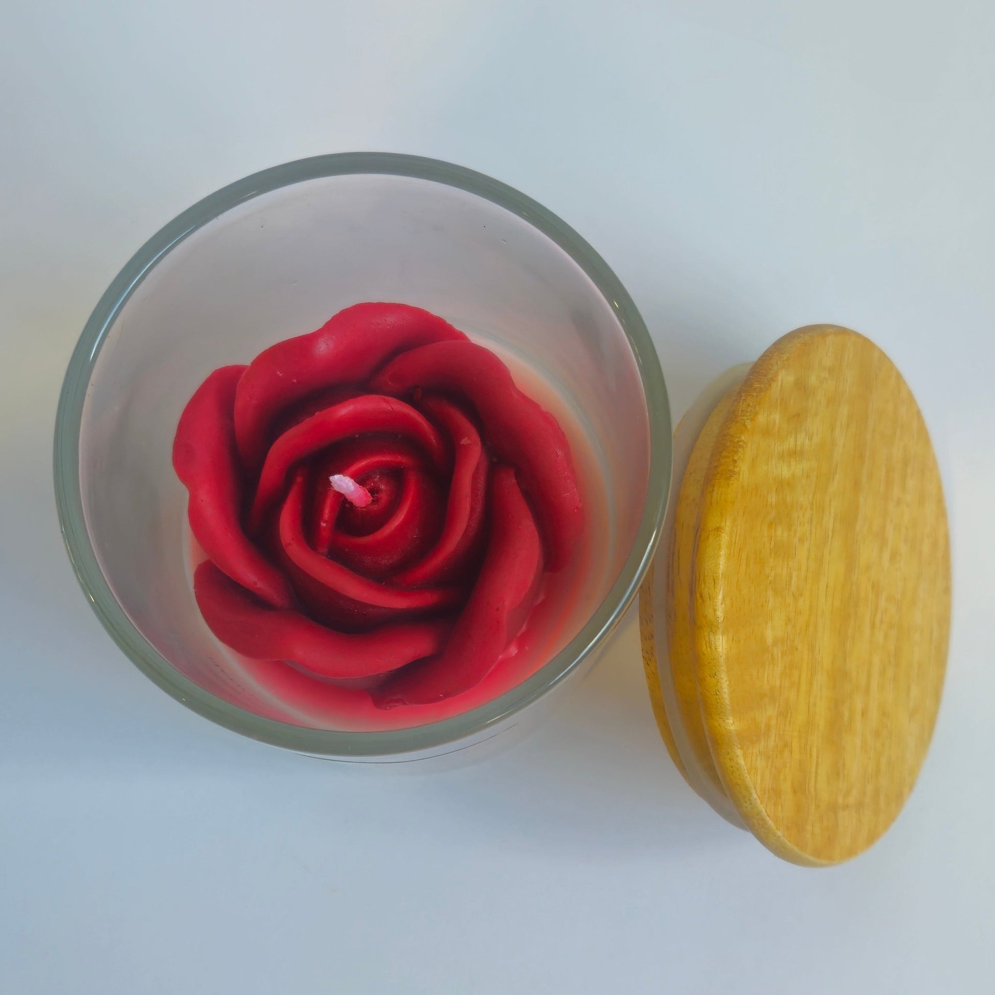 Glass container with a red rose and a yellow object on a white background