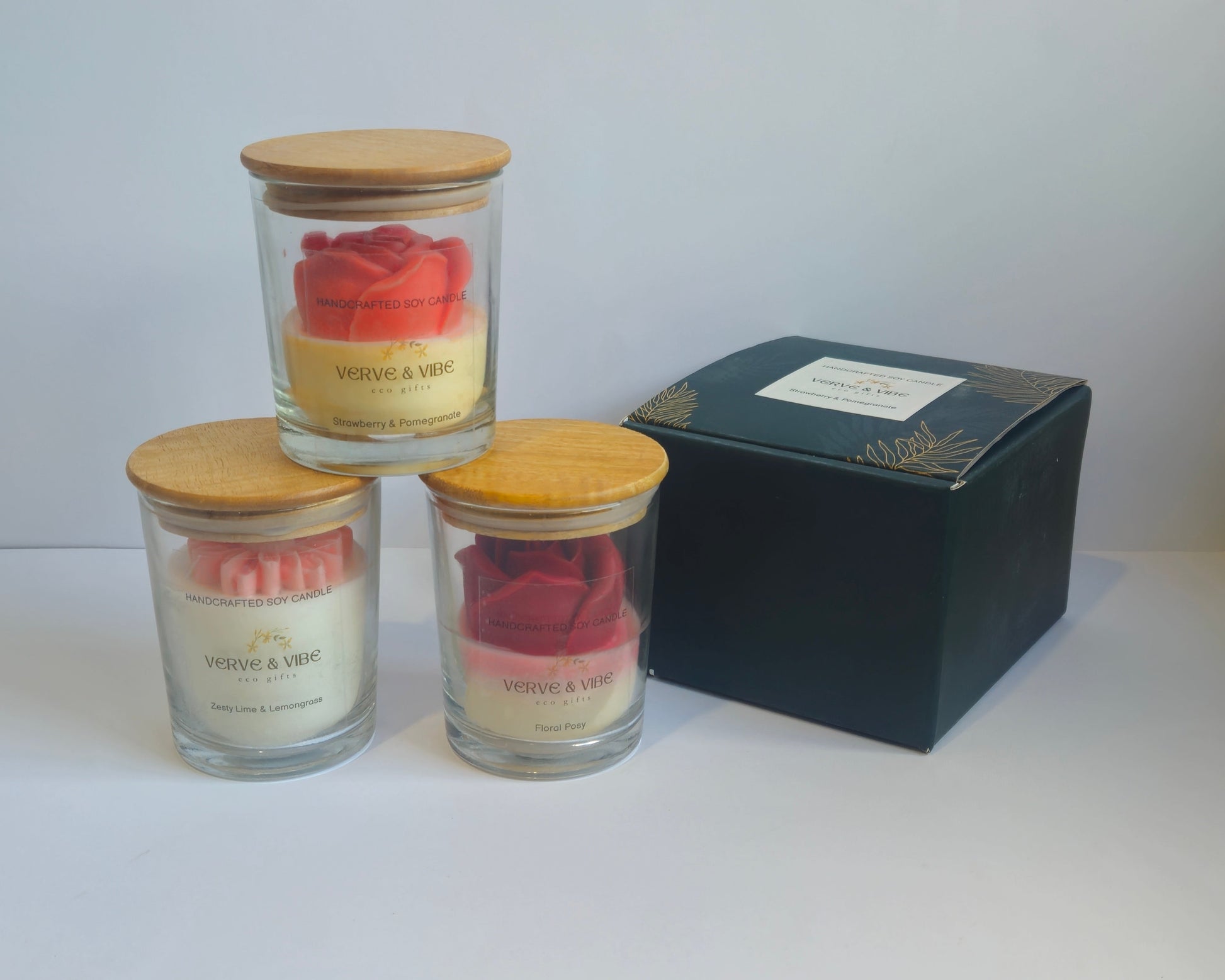 Three small jars with lids on a white surface next to a black box.