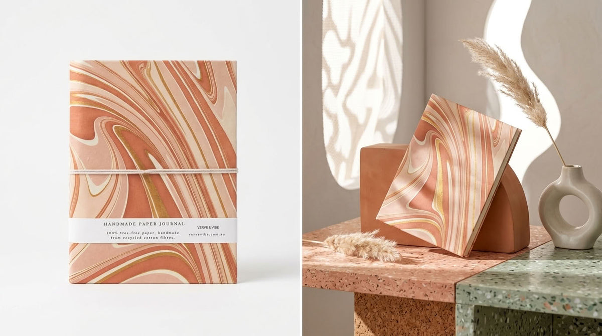 A notebook with a peach, beige, and cream marble swirl pattern is shown in two views: one standing upright on a white background with a thin twine wrap and label, and another leaning on a terracotta block on a styled interior table with dried grass and a vase.