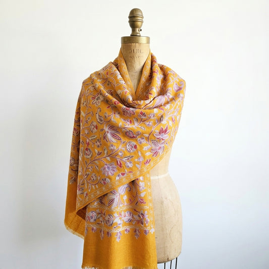 Yellow floral patterned scarf on a mannequin against a white background