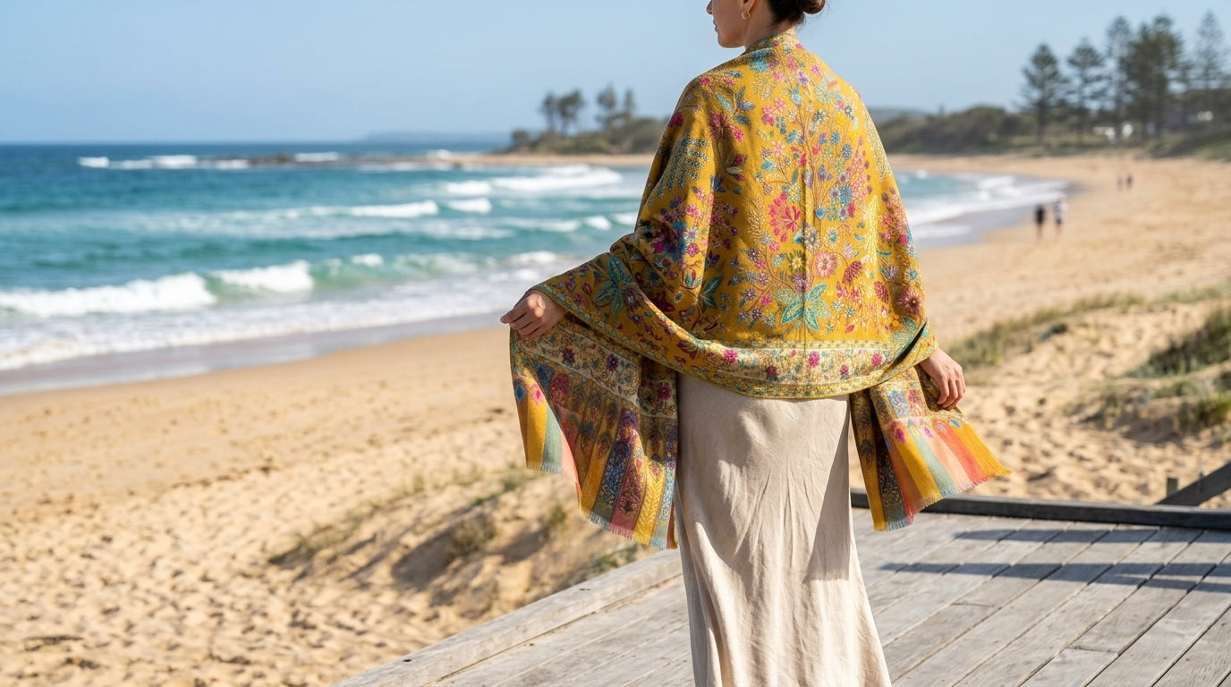 Woman standing on a beach with a colorful shawl draped over her shoulders
