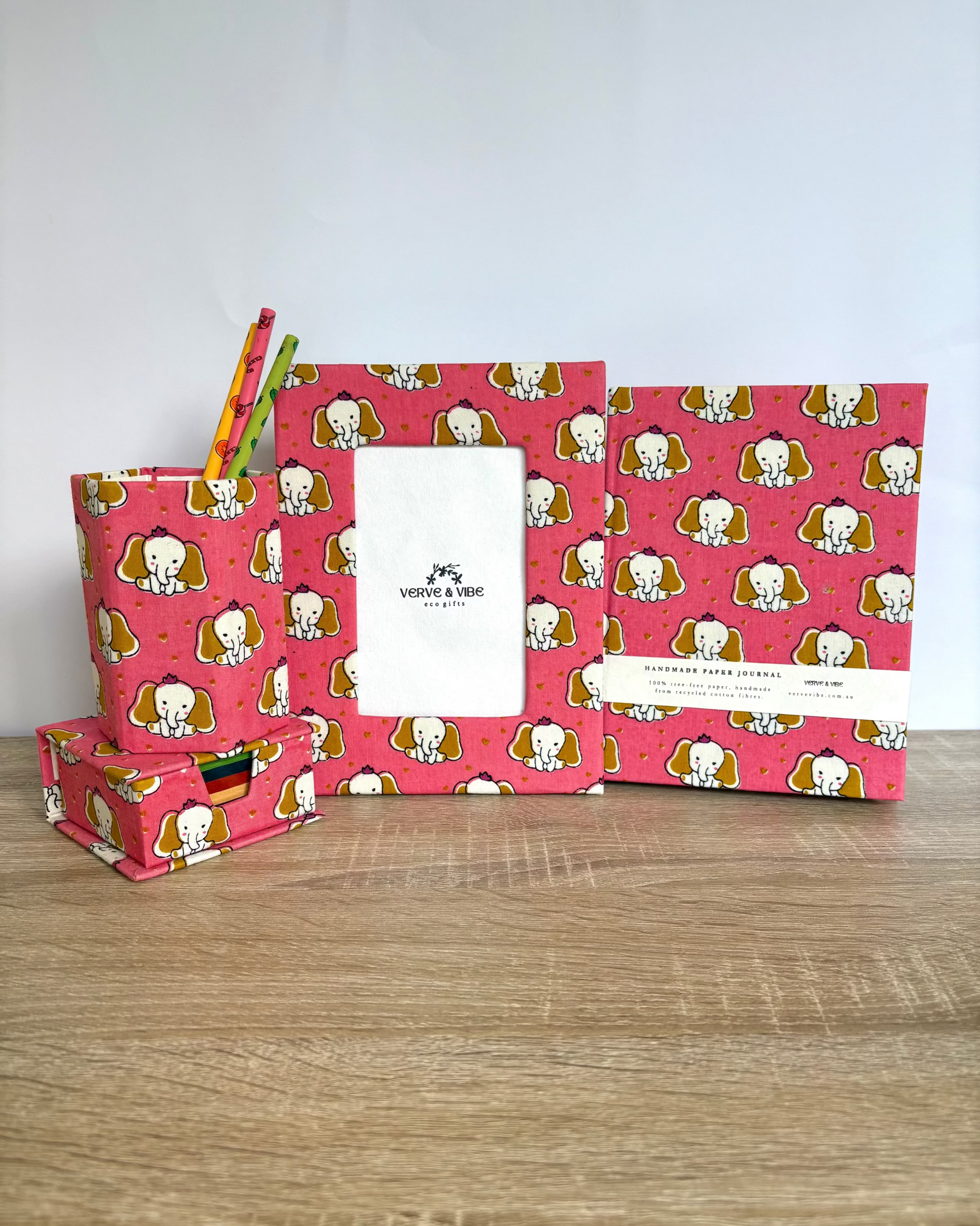 Set of stationery items with pink elephant pattern on a wooden surface