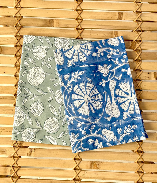 Two floral-patterned towels, one green and one blue, on a wooden surface.