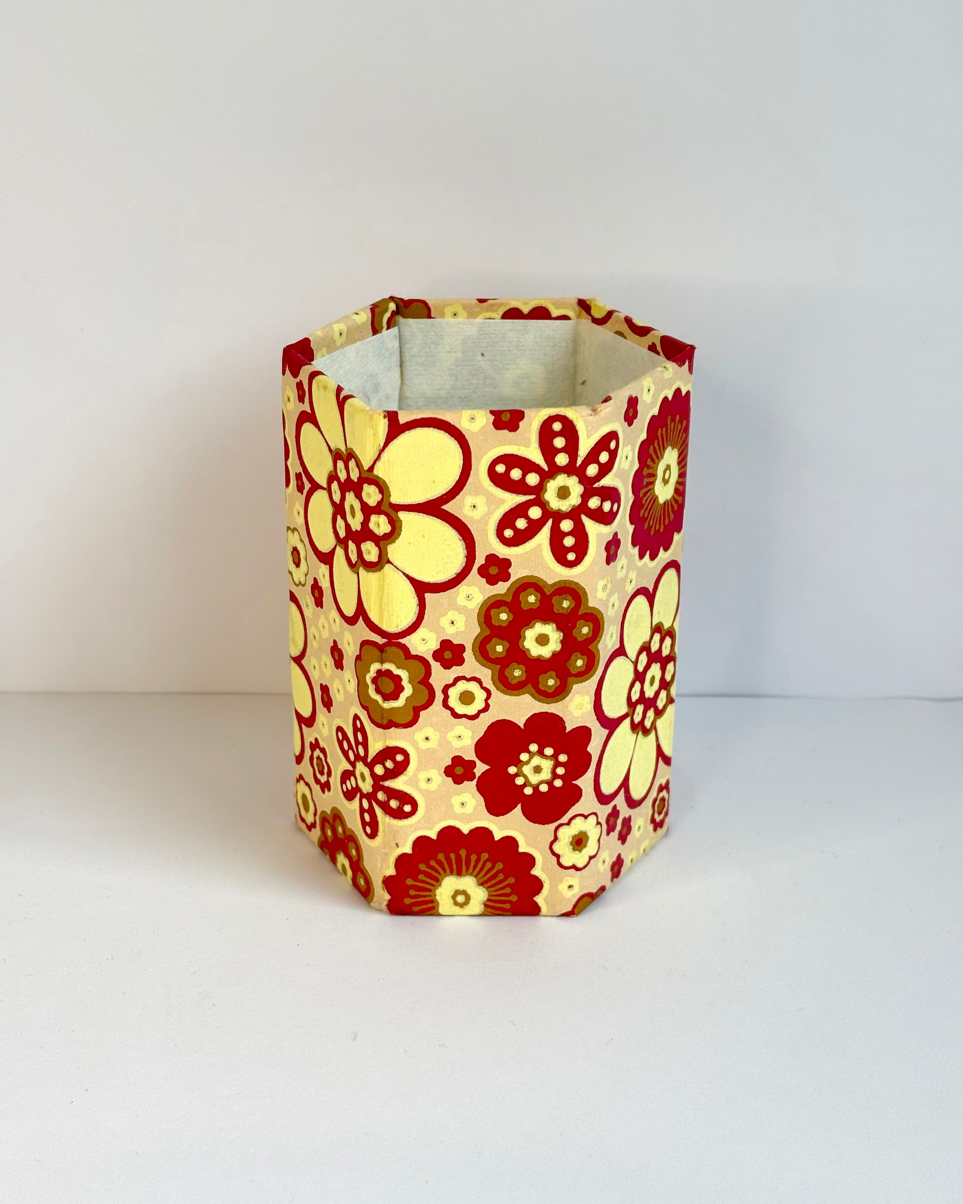 Hexagonal lampshade with red and yellow floral pattern on a white background