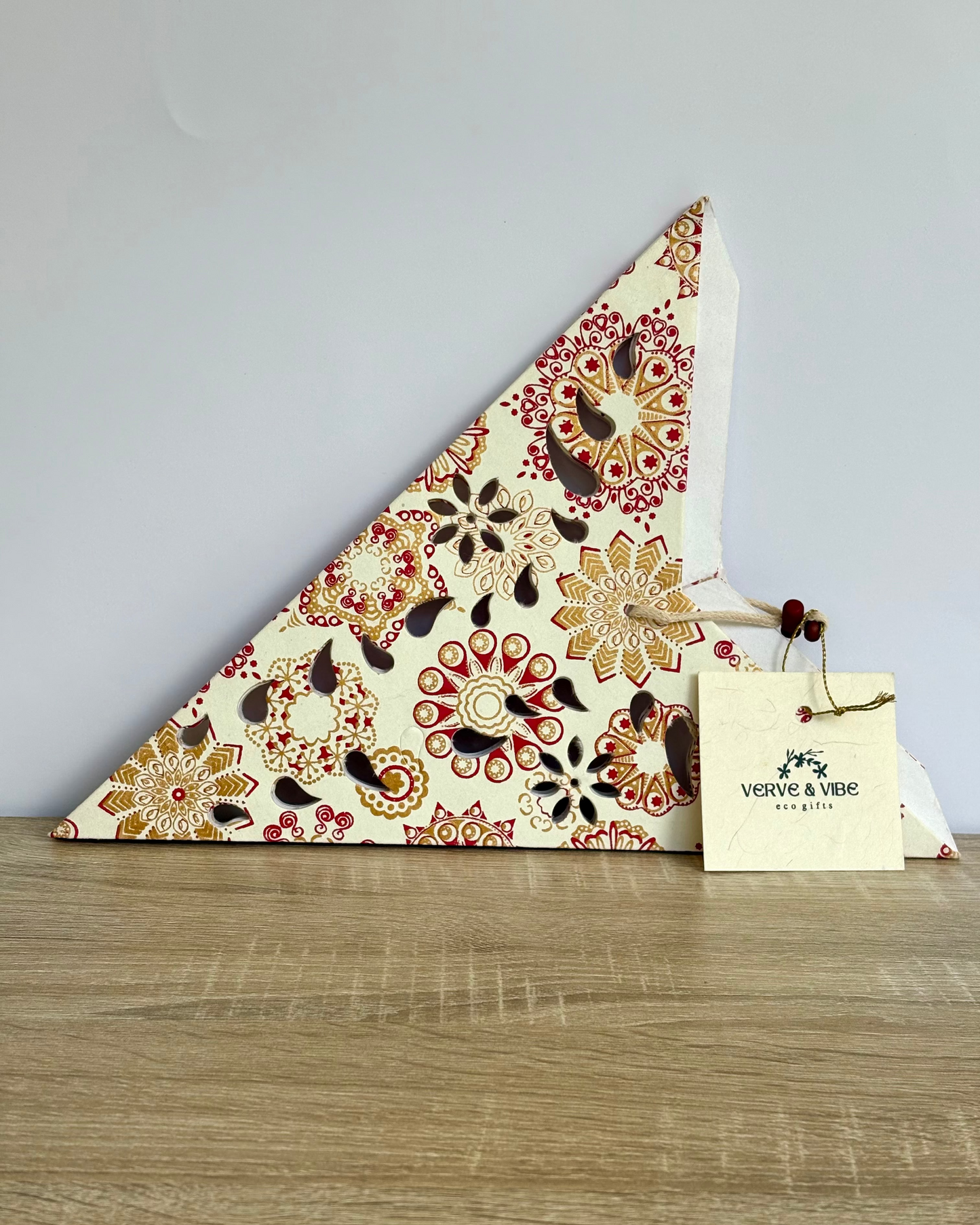 Decorative triangle with floral pattern on a wooden surface, featuring a brand tag.