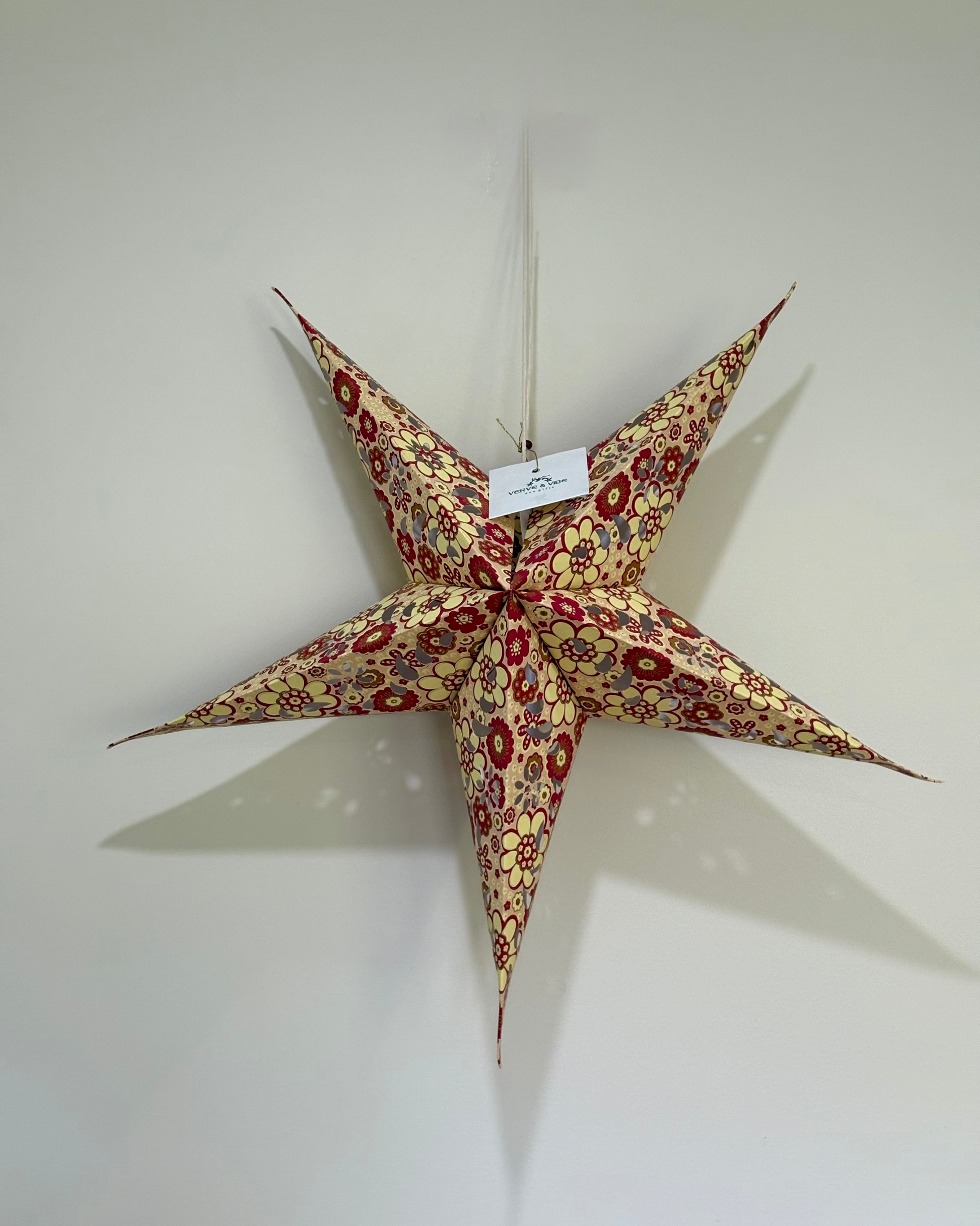 Decorative star-shaped lantern with floral pattern on a plain wall