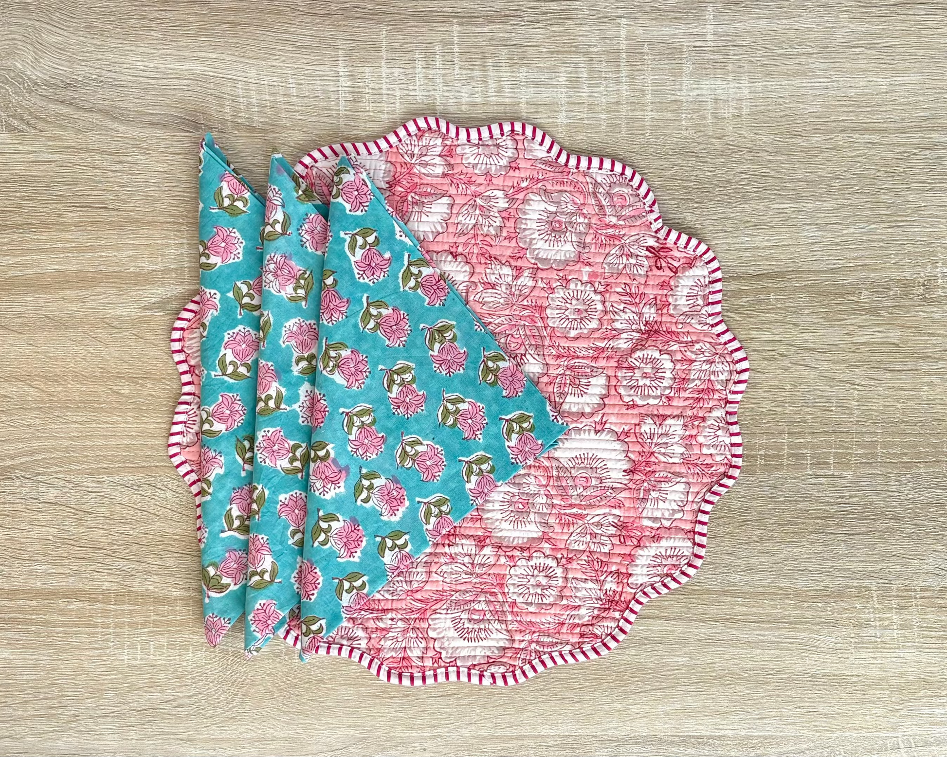 Two fabric placemats with floral patterns on a wooden surface