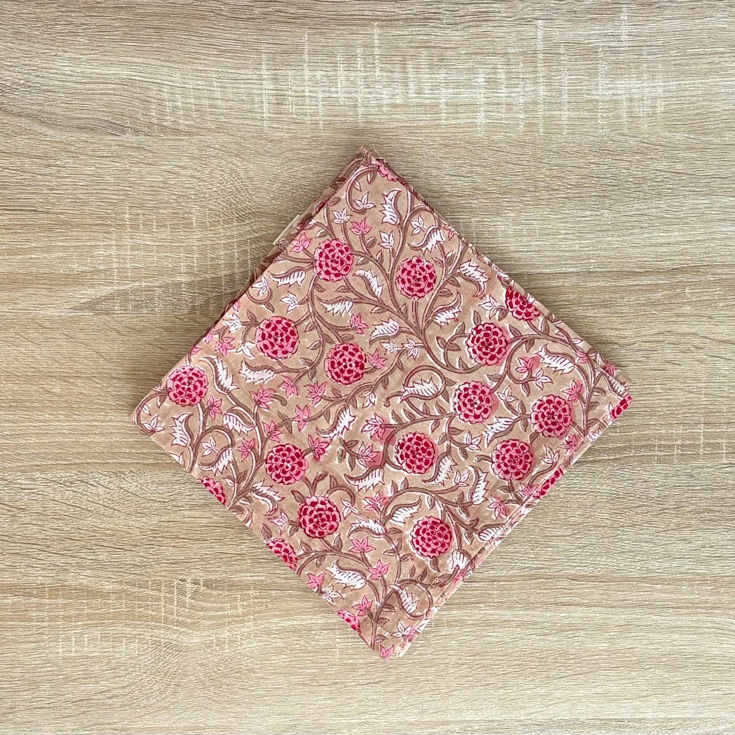 Folded pink fabric with floral pattern on a wooden surface