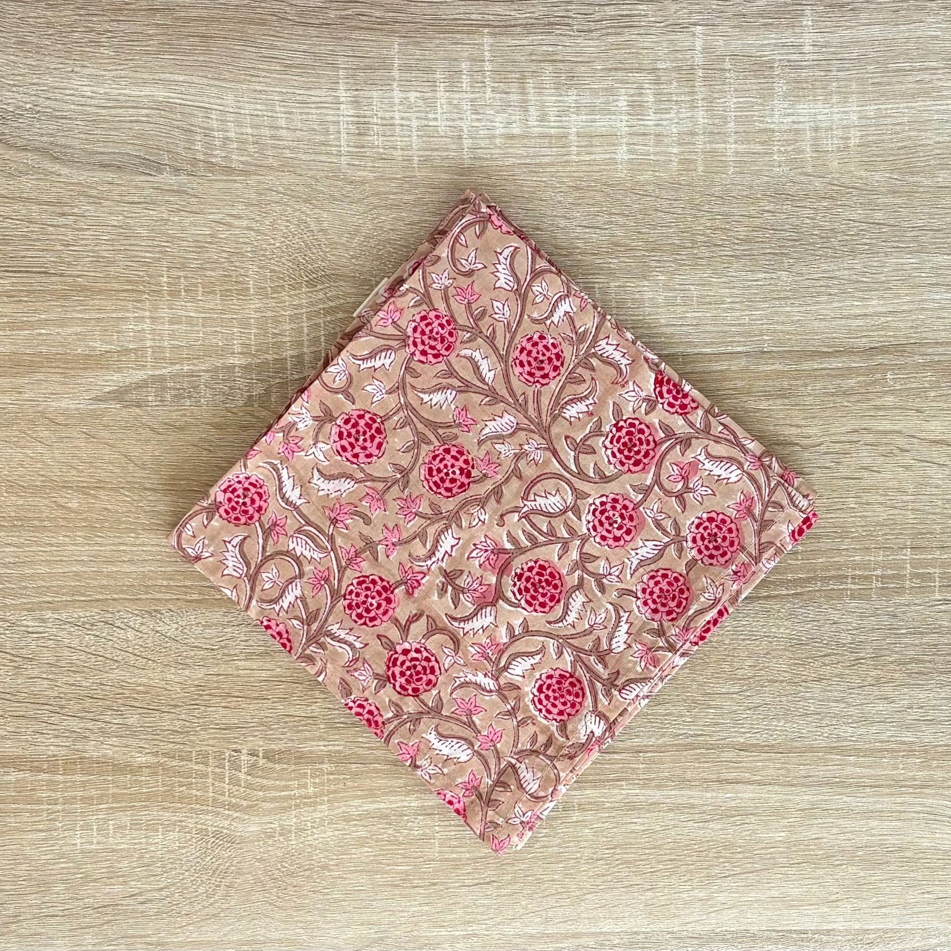 Folded pink fabric with floral pattern on a wooden surface