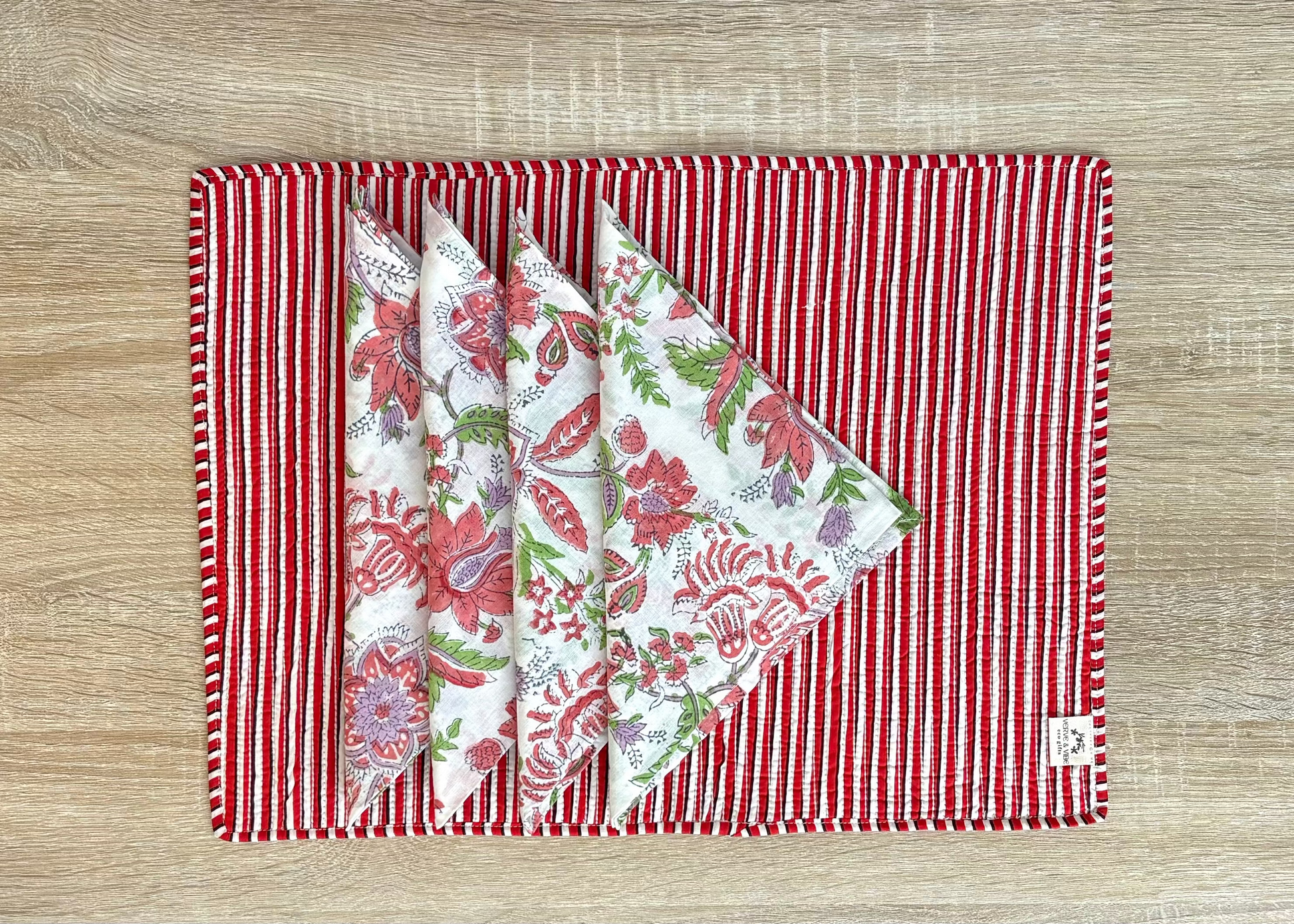 Set of floral-patterned napkins on a red and white striped placemat on a wooden surface