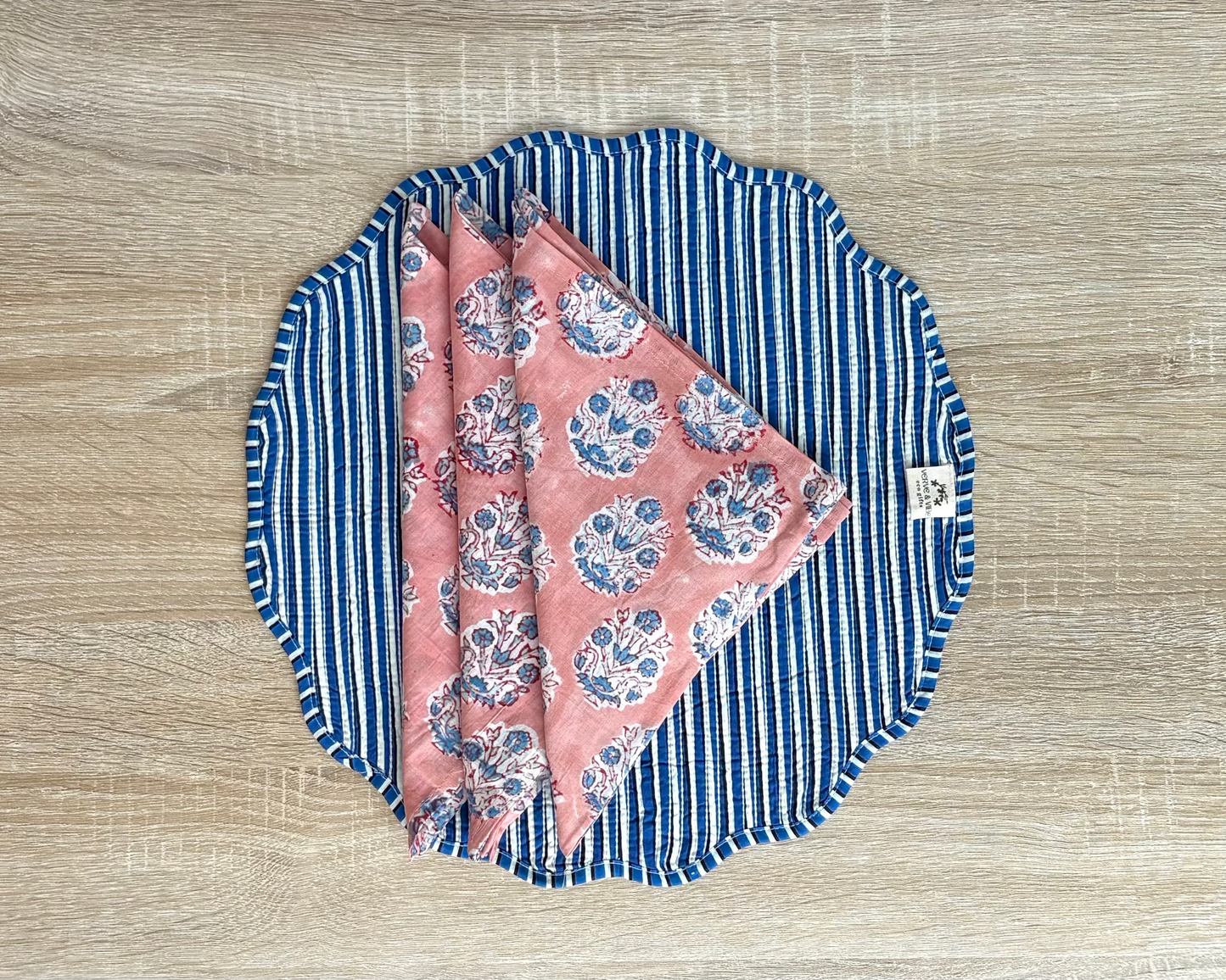 Fabric with blue stripes and pink floral pattern on a wooden surface
