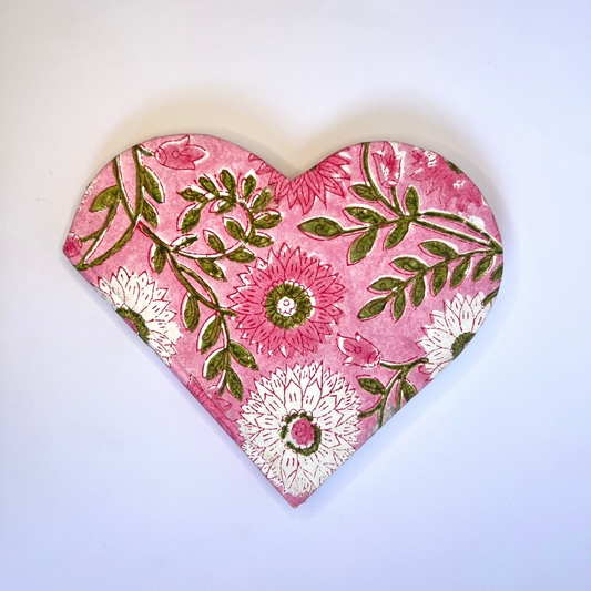Heart-shaped pink and green floral decorative item on a light blue background