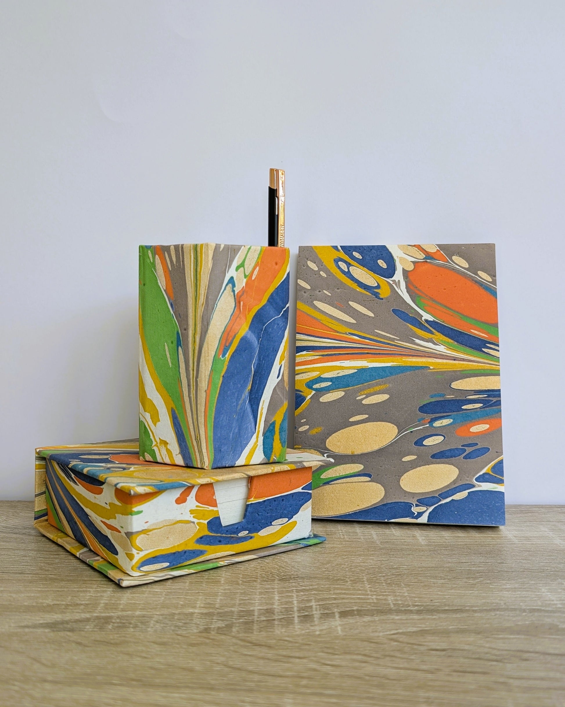 Colorful marbled notebooks with a pen on a wooden surface