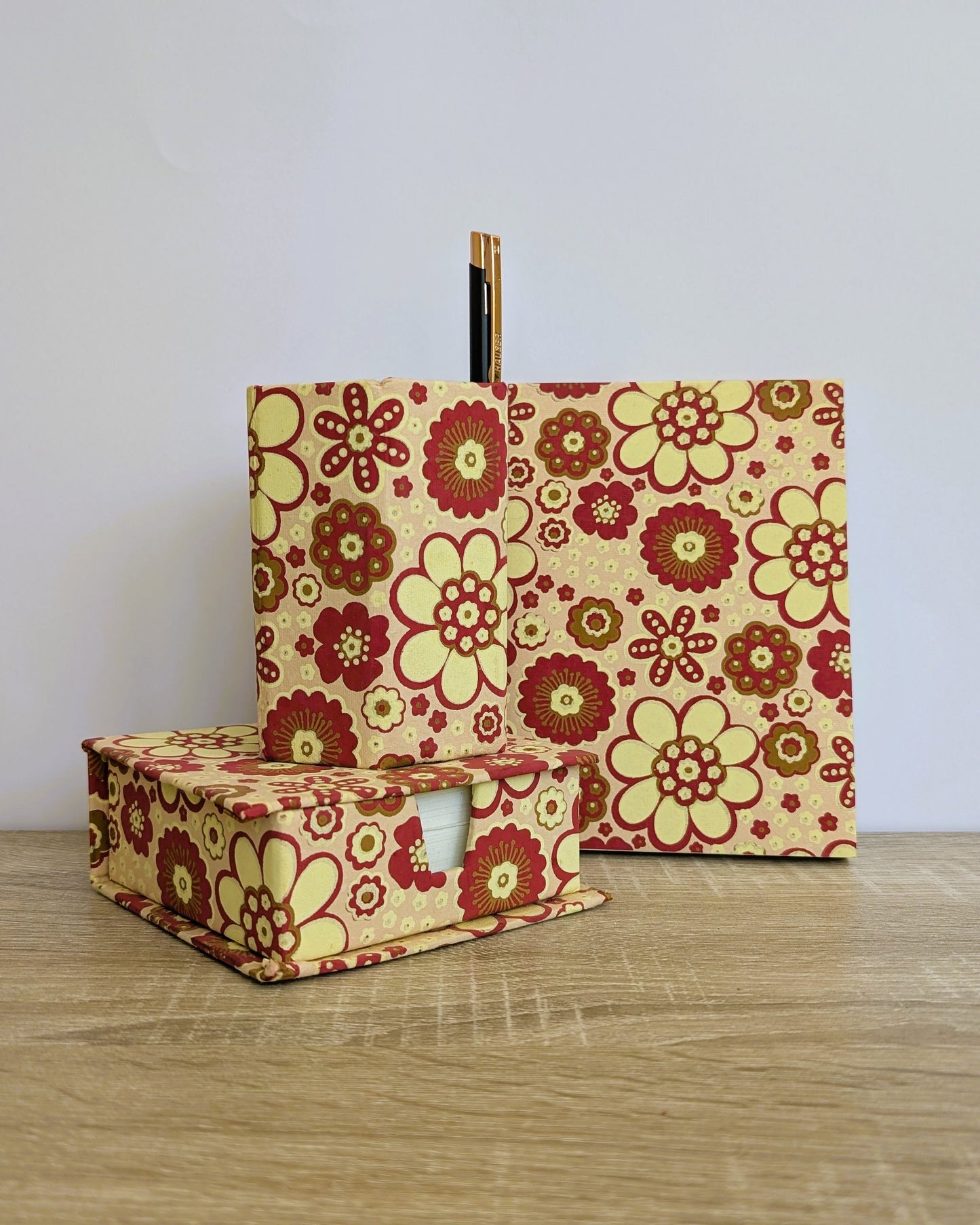 Two floral-patterned boxes on a wooden surface with a white background